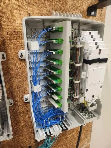 Open fiber distribution cabinet with organized blue fiber leads and connector panels