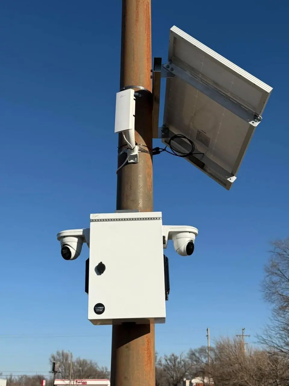 Pole-mounted outdoor surveillance system with dual cameras, equipment enclosure, and solar panels