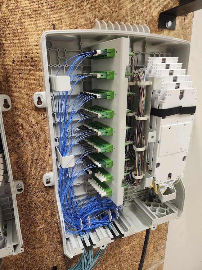 Open fiber distribution cabinet with routed blue fiber pigtails and connector panels