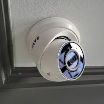 Compact white surveillance camera mounted near a ceiling